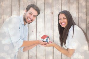 A young couple holding a model house. Protective Property Trust from Cedar Wills & Trusts